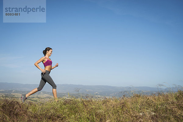 Mixed race woman running in rural landscape