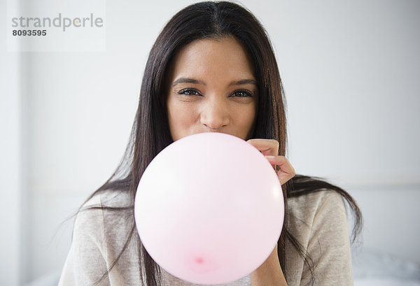 Mixed race woman blowing up balloon