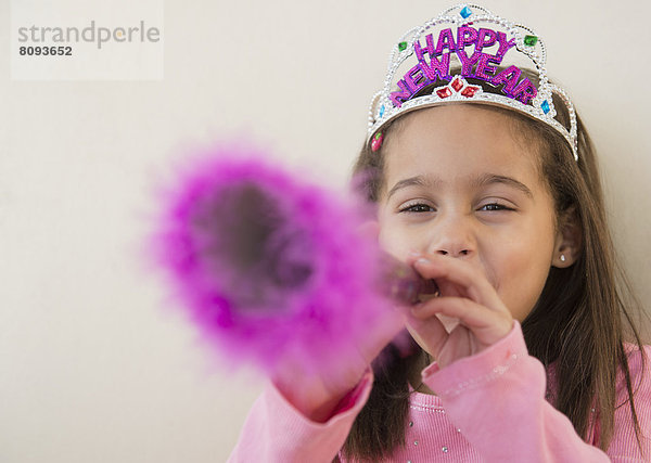 Hispanic girl using noise maker at New Years' party