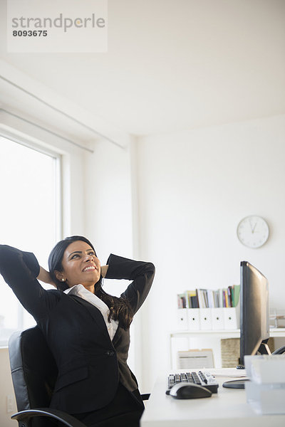 Indian businesswoman stretching at desk