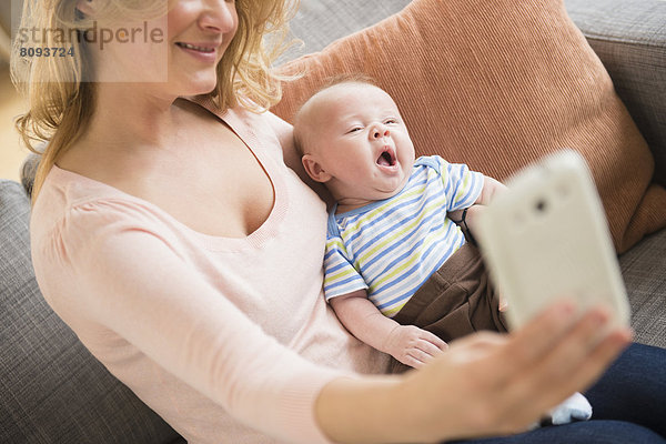 Caucasian mother taking picture of herself and baby