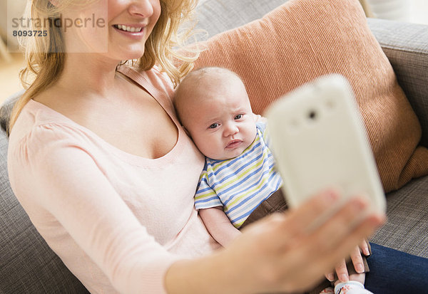 Caucasian mother taking picture of herself and baby