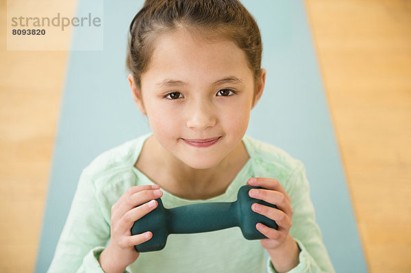 Mixed race girl holding weight on yoga mat