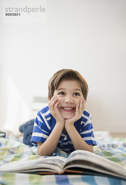 Hispanic boy reading on bed