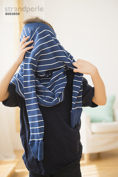 Hispanic boy pulling on sweater