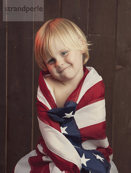 Caucasian boy wrapped in American flag