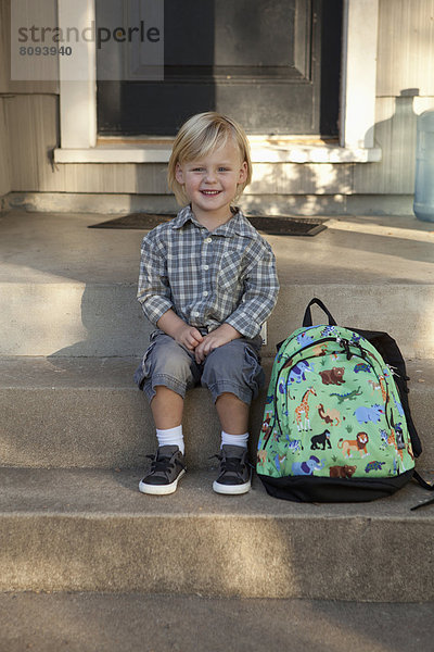 Caucasian boy with backpack on front steps