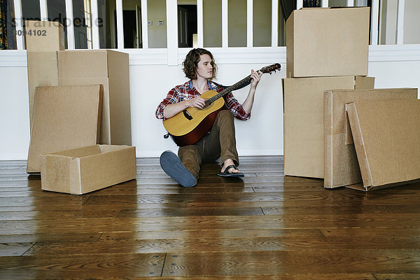 Caucasian man playing guitar in new home