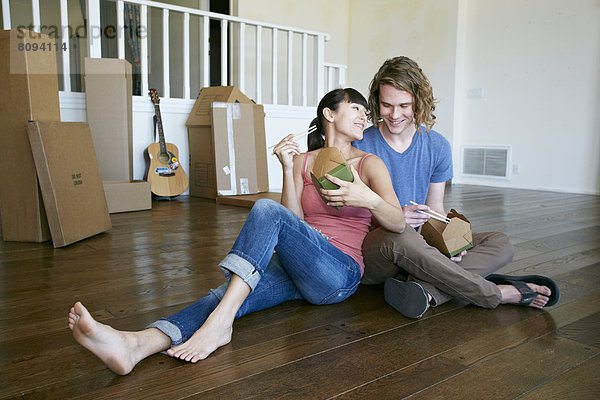 Couple eating take out food in new home
