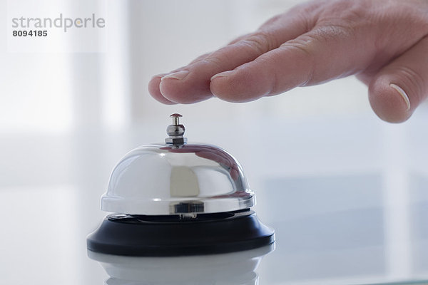 Hispanic man ringing service bell on desk