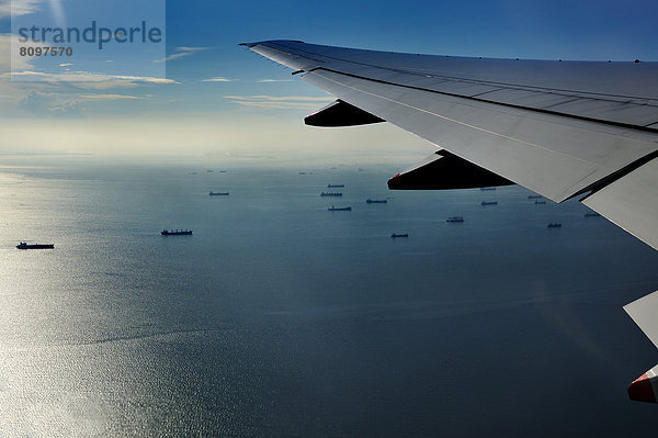 Tragfläche und Sicht auf Hafengebiet von Jakarta beim Anflug