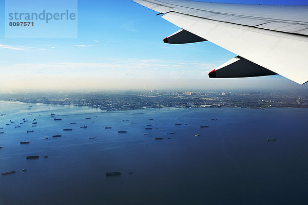 Tragfläche und Sicht auf Hafengebiet von Jakarta beim Anflug