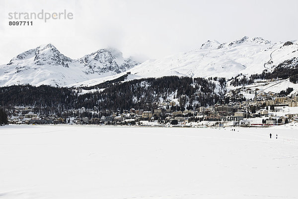 Panoramaaufnahme  zugefrorener St. Moritzersee mit Stadt und Bergen
