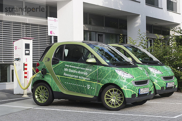 Elektroautos stehen zum Aufladen an der Steckdose vor der Telekom-Zentrale