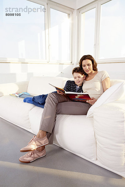 Mutter und Sohn mit Buch auf Sofa
