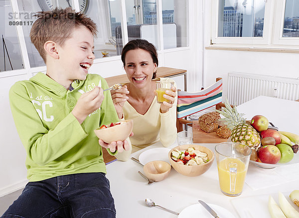 Mutter und Sohn essen frisches Obst und Müsli