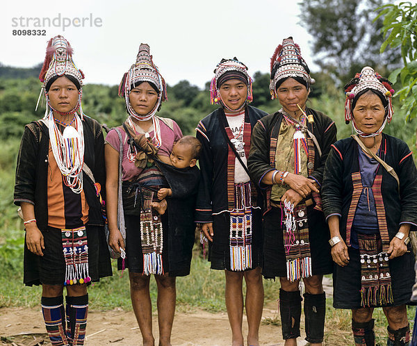 Fünf Akha Frauen in einem Bergdorf mit traditioneller Kleidung und Kopfbedeckung