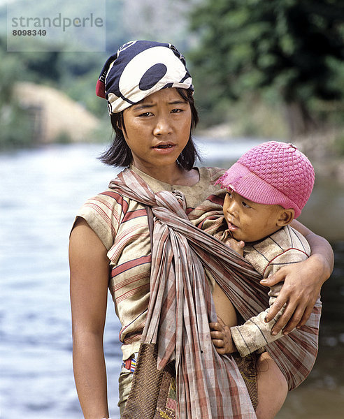 Junge Karen-Frau mit Kind beim Stillen  am Fluss Kok