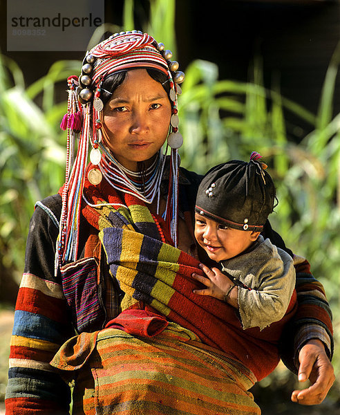 Junge Akha-Frau und Kind mit traditioneller Kleidung und Kopfbedeckung
