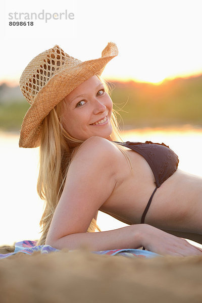 Junge Frau liegt im Bikini am Strand
