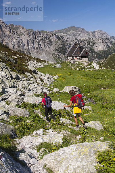 Zwei Wanderer  hinten die Berghütte Rifugio Garelli