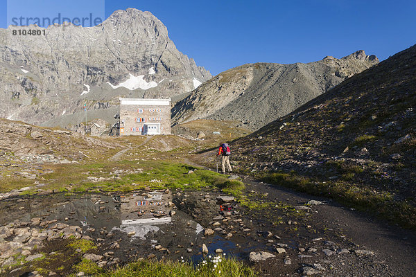 Wanderer an der Berghütte Rifugio Gastaldi  hinten der Berg Uia di Bessanese