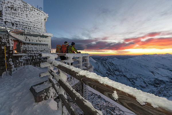 Zwei Bergsteiger beobachten den Sonnenaufgang an der Erzherzog-Johann-Hütte auf dem Großglockner