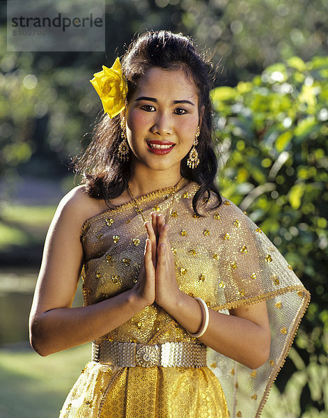 Der Wai  thailändische Geste der Begrüßung  junge Frau in traditionellem Kostüm  Rose Garden