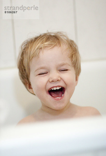Lachendes blondes Mädchen in der Badewanne