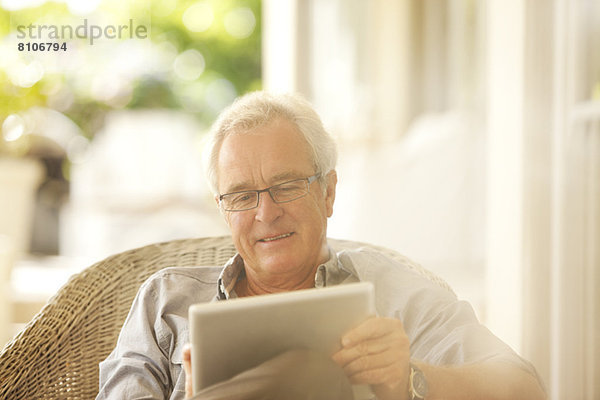 Senior Mann mit digitalem Tablett auf der Terrasse