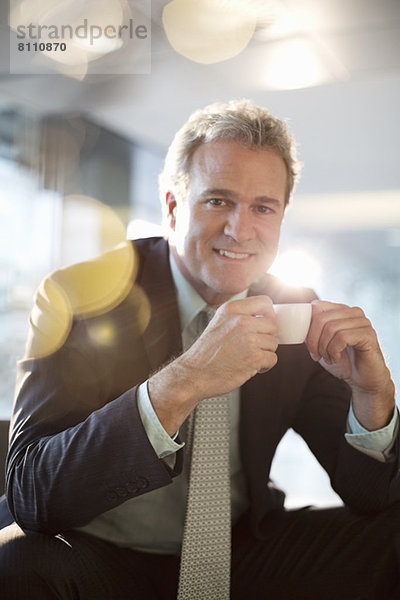 Porträt eines lächelnden Geschäftsmannes beim Espresso trinken