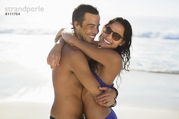 Porträt eines glücklichen Paares  das sich am Strand umarmt.