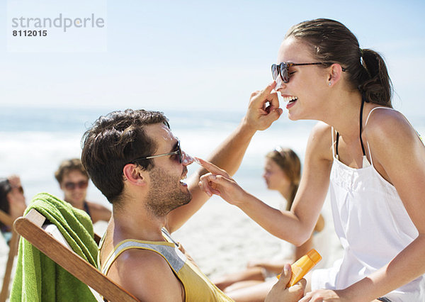 Paar  das sich gegenseitig die Nase am Strand mit Sonnencreme eincremt.