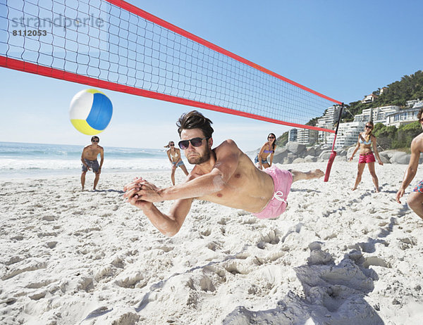 Mann taucht für Volleyball am Strand