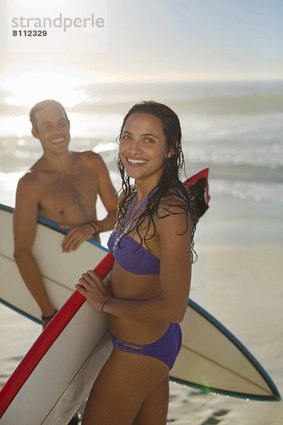 Portrait eines glücklichen Paares mit Surfbrettern am Strand