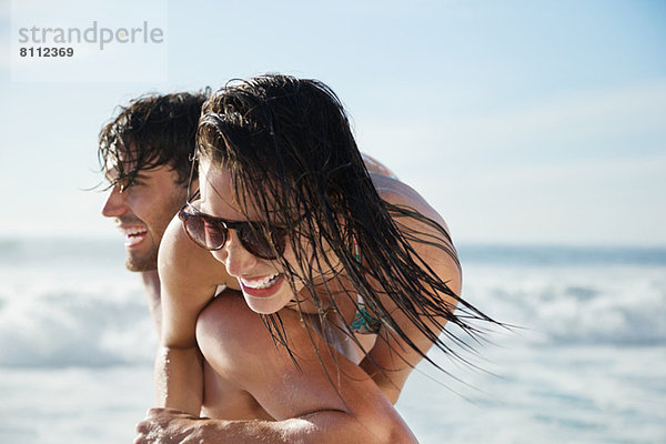 Mann mit begeisterter Frau am Strand