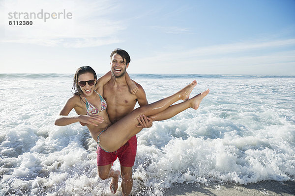 Enthusiastischer Mann mit Frau am Strand