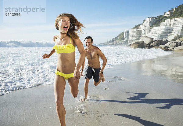 Mann jagt glückliche Frau am Strand