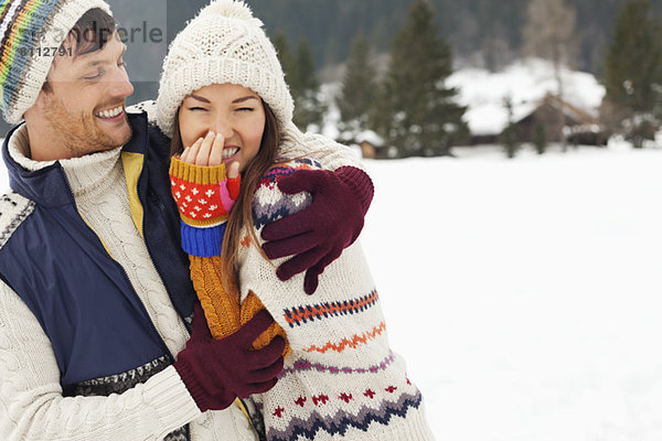 Paar lachend und umarmend im Schneefeld