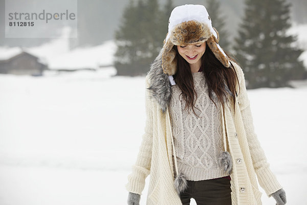 Lächelnde Frau mit Pelzmütze im Schneefeld