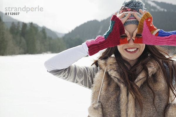 Porträt einer lächelnden Frau mit kreisenden Augen und Fingern im Schneefeld