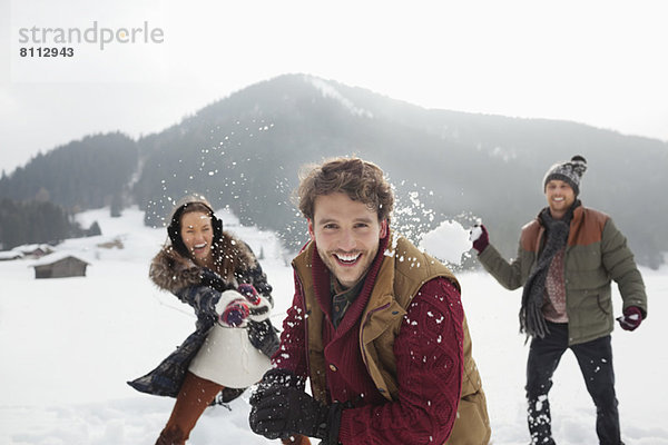 Porträt von verspielten Freunden  die Schneebälle ins Feld werfen