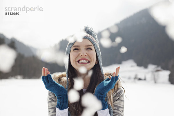Fröhliche Frau genießt fallenden Schnee auf dem Feld