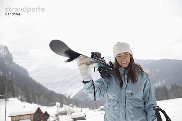 Porträt einer begeisterten Frau mit Skiern im Schneefeld