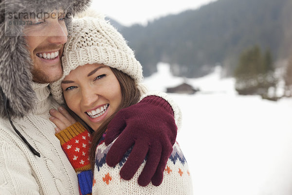 Nahaufnahme Porträt eines glücklichen Paares  das sich im Schnee umarmt.