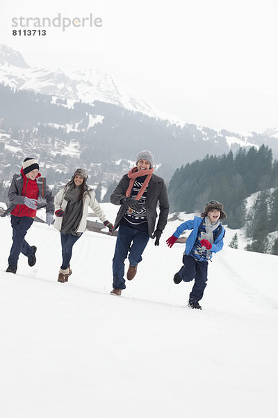 Glückliche Familie beim Laufen im Schneefeld