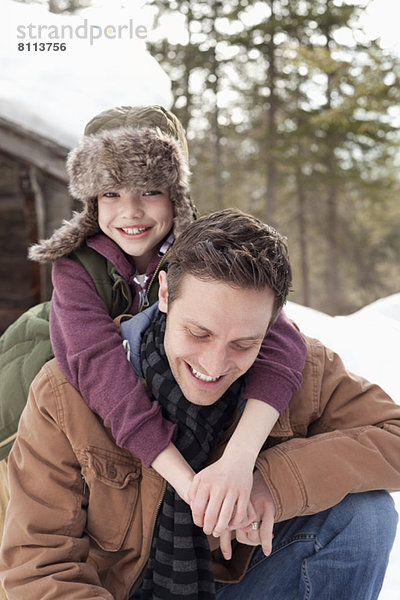 Porträt eines glücklichen Sohnes  der den Vater im Schnee umarmt.