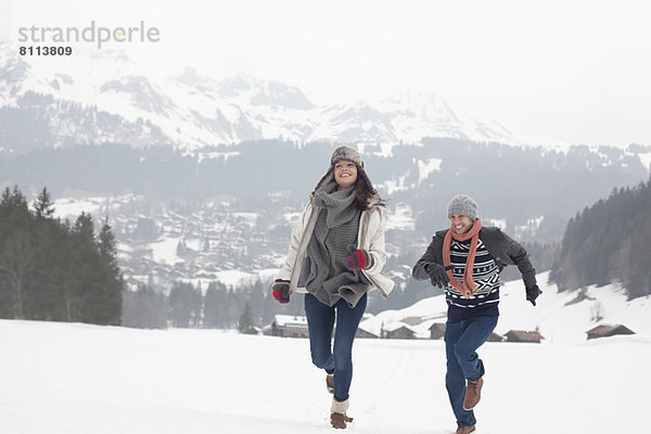 Glückliches Paar läuft im verschneiten Feld