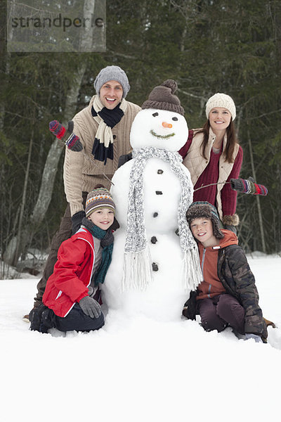Porträt einer glücklichen Familie mit Schneemann