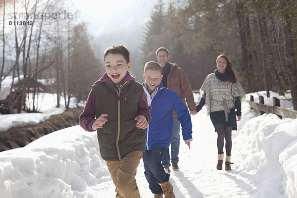 Glückliche Familie beim Laufen in der verschneiten Gasse